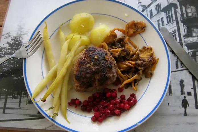 Pan-fried beef patty with potatoes, wax beans, raw-stirred lingonberries, and red-yellow funnel chanterelle mushrooms. Photo: Ankara (CC BY-SA 3.0)