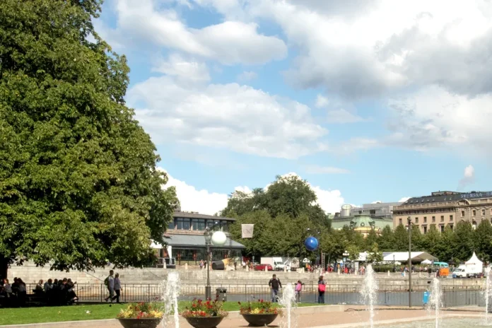 The statue Solsångaren surrounded by summer greenery in Strömparterren. View toward Kungsträdgården, and a glimpse of the Royal Opera in the background. Photo: Rhododendrites (CC BY-SA 4.0)